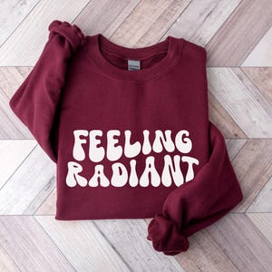 a red sweatshirt with the words feeling radant printed on it
