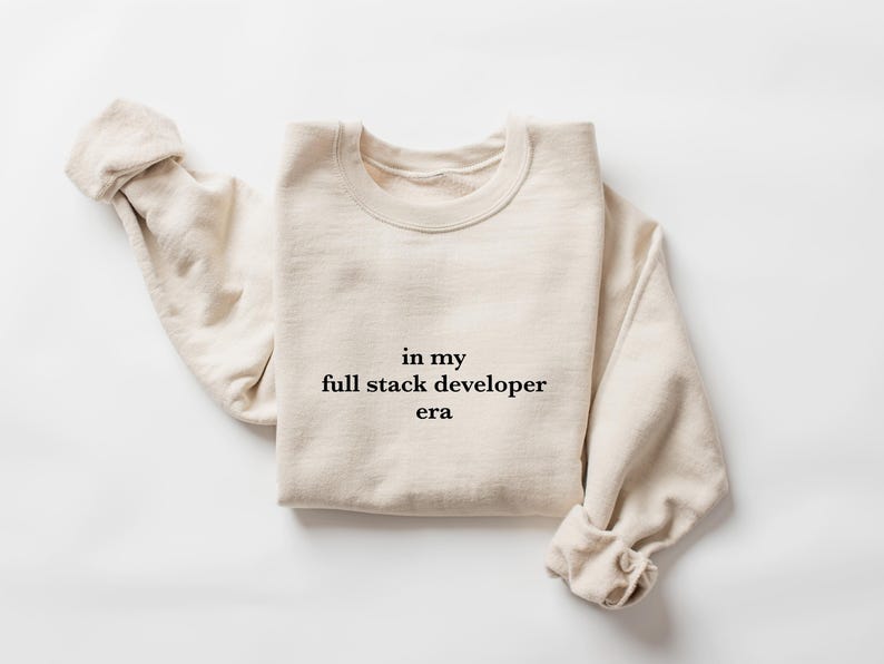 A beige sweater with the text "in my full stack developer era" printed on it.