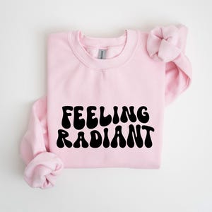 a pink sweatshirt with the words feeling radiant printed on it