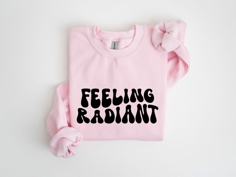 a pink sweatshirt with the words feeling radiant printed on it