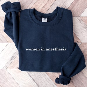 Könnte beinhalten: Ein marineblauer Sweatshirt mit dem Text "women in anesthesia" in weiß auf der Vorderseite.