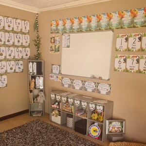 May include: A classroom decorated with a jungle theme. The walls are covered in colorful posters with letters, numbers, and days of the week. There are also shelves with books and toys. The room is bright and cheerful.