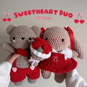May include: A crocheted teddy bear and bunny wearing red overalls and a dress with a bouquet of red roses. The caption reads "Sweetheart Duo PDF Pattern".