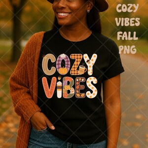 May include: Black t-shirt with the words "COZY VIBES" in a fall-themed design. The letters are decorated with pumpkins, coffee cups, and autumn leaves. The words "FALL PNG" are written vertically in the upper right corner.