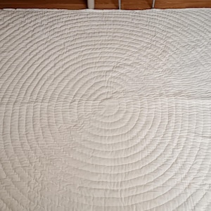 Peut inclure: Jeté de canapé blanc matelassé avec un motif circulaire de piqûres.