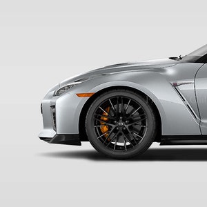 May include: A silver sports car with black wheels and orange brake calipers. The car is viewed from the side, with the front wheel and fender in focus.