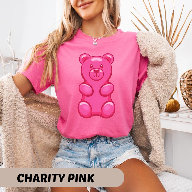 Puede incluir: Camiseta rosa con un dise&ntilde;o de osito de goma. La camiseta es de color rosa brillante, con el texto "CHARITY PINK" en la parte inferior. El osito de goma es de color rosa brillante.