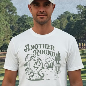 May include: White t-shirt with the text "Another Round" and a cartoon disc golf design. The design includes a disc with a face, a beer stein, a tree, and a disc golf basket.