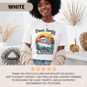 May include: White t-shirt with a colorful graphic featuring a ship wearing a Santa hat, the text "Dear Santa 2025", and "We Traded Silent Nights for Sea Nights". The shirt is worn by a person.