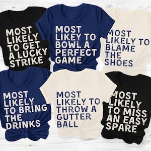 Könnte beinhalten: Eine Sammlung von sechs kurzärmeligen T-Shirts in Schwarz, Marineblau und Creme. Jedes Shirt zeigt weißen oder dunkelblauen, abgenutzten Text mit Bowling-Sprüchen wie Most Likely To Get A Lucky Strike, Bowl A Perfect Game, Blame The Shoes, Bring The Drinks, Throw A Gutter Ball und Miss An Easy Spare.