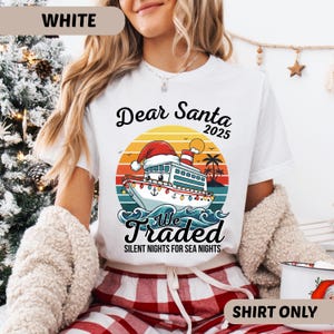 May include: White t-shirt with a colorful graphic featuring a cruise ship wearing a Santa hat, set against a sunset backdrop. Text reads "Dear Santa 2025" and "We Traded Silent Nights for Sea Nights". A festive holiday-themed shirt.