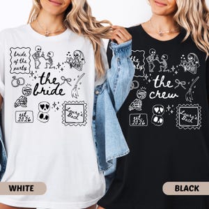 Könnte beinhalten: Ein weißes T-Shirt und ein schwarzes T-Shirt mit einem Grafikdruck von Skeletten, einem Weinglas, Ringen und Text. Das weiße Shirt zeigt 'bride of the party', 'the bride', 'est. 2026' und 'Laura's Bach'. Das schwarze Shirt zeigt 'the crew' und 'est. 2026'.
