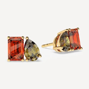 May include: A pair of stud earrings set in yellow gold, each featuring an emerald-cut orange gemstone paired with a pear-cut olive green gemstone. The stones are held in place by gold prongs, with one earring shown from the front and one from the side.