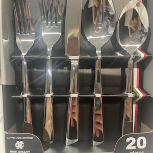 May include: A close-up of a box containing a 20-piece stainless steel cutlery set. The set includes forks, knives, and spoons. The box is black with a silver trim and features the text "Hotel Collection" and "High Quality Stainless Steel".
