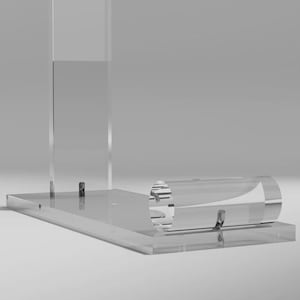 Peut inclure: Un présentoir transparent en acrylique avec une base rectangulaire et un support vertical. Une pièce cylindrique est fixée à la base. Le présentoir est conçu pour mettre en valeur des articles, avec une esthétique minimaliste et moderne.