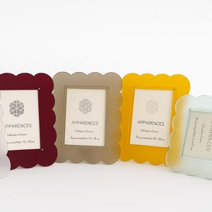 May include: A collection of five colorful photo frames with scalloped edges. The frames are in shades of white, burgundy, taupe, yellow, and light blue. Each frame has a white insert with the word "APPARANCES" and a geometric design.