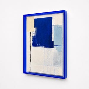 Peut inclure: Une œuvre d'art murale rectangulaire sur toile présentant des formes géométriques abstraites dans des tons de bleu profond, bleu clair et crème. L'œuvre est encadrée par un cadre bleu cobalt brillant, vue sous un angle légèrement latéral.