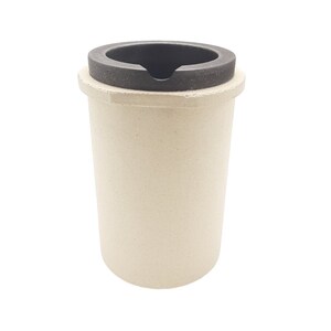 May include: A white ceramic crucible with a black ceramic lid. The crucible is used for melting metal.