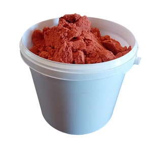 Może przedstawiać: Biały plastikowy kubeł wypełniony dużą ilością czerwonego proszku.