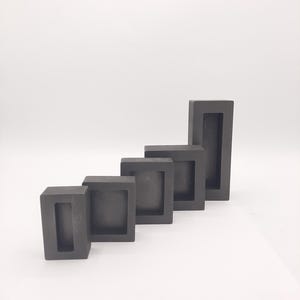 Könnte beinhalten: Fünf schwarze Graphitformen in verschiedenen Größen, in einer Reihe vom größten zum kleinsten angeordnet. Die Formen sind rechteckig mit einer rechteckigen Öffnung in der Mitte.