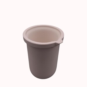 May include: A matte off-white ceramic crucible with a cylindrical body and a rounded base. The vessel features a wide, circular rim with a small, triangular pouring spout extending from one side. The interior and exterior surfaces are uniform.