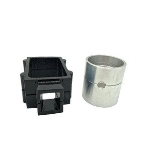 May include: Two metal components. One is a black, rectangular, open-top structure with a square opening. The other is a silver, cylindrical piece with a split and a small hole. Both are set against a white background.