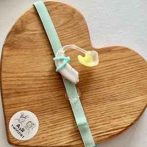 May include: A set of three ceramic mugs with a speckled, cream-colored glaze. Each mug features a different hand-painted design: a blue and green leaf, a yellow flower, and a red berry. The mugs have a simple, rounded shape.