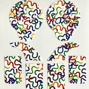 May include: A set of white nail art stickers with a colorful squiggly line pattern in red, orange, yellow, green, blue, and purple. The set includes two large oval shapes, two curved shapes, and three rectangular shapes.