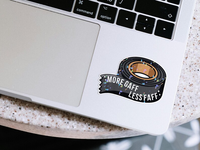 K&ouml;nnte beinhalten: Ein Aufkleber mit einer Rolle schwarzem Gaffaband mit braunem Kern. Der Aufkleber hat den wei&szlig;en Text "MORE GAFF LESS FAFF". Der Aufkleber befindet sich auf einem Laptop.