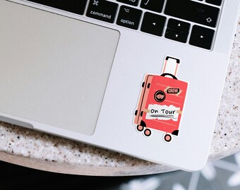 Könnte beinhalten: Ein roter Kofferaufkleber mit dem Text "CREW" und "ON TOUR" auf weißem Hintergrund. Der Koffer hat einen schwarzen Griff und Räder.