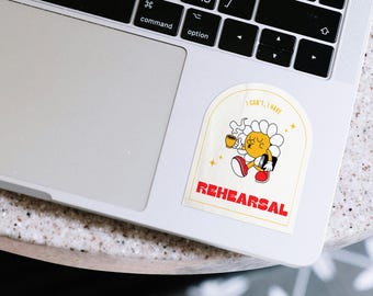 Könnte beinhalten: Ein gelber und roter Aufkleber mit einer Comicfigur, die eine Tasse Kaffee und ein Buch hält. Der Aufkleber sagt "Ich kann nicht, ich habe Probe".
