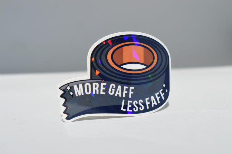 K&ouml;nnte beinhalten: Aufkleber mit einem Klebebandrollen-Design in Dunkelblau und Braun. Der Text "MORE GAFF LESS FAFF" ist wei&szlig;. Der Aufkleber hat einen holografischen Effekt.