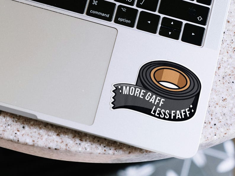 K&ouml;nnte beinhalten: Ein Aufkleber mit einer Rolle schwarzem Gaffer-Tape mit braunem Kern. Der Aufkleber tr&auml;gt den Text "MORE GAFF LESS FAFF" auf einem schwarzen Banner. Der Aufkleber befindet sich auf einem Laptop.