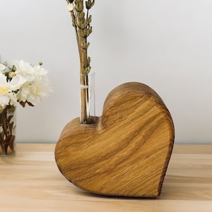 Wooden vase made of oak wood shaped like a heart that lies with test tube