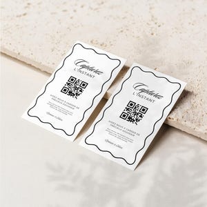 May include: Two white rectangular cards with black text and a QR code. The cards have a decorative black border. The text on the cards reads "Capturez L'Instant" and "Aidez-nous a garder de précieux souvenir".