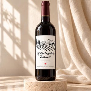 May include: A dark glass wine bottle with a white label featuring a black line drawing of a vineyard and house. The text reads: Et si je t'appelais Parrain? pour toute la vie, with a small red heart and the text MIS EN BOUTEILLE AVEC AMOUR.