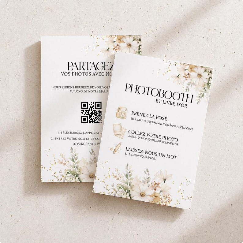 May include: Two white cards with floral designs and text. One card says "PARTAGEZ VOS PHOTOS AVEC NO" and includes a QR code. The other card says "PHOTOBOOTH ET LIVRE D'OR" with instructions. The cards have a soft, elegant aesthetic.