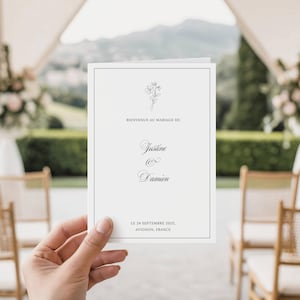 Peut inclure: Une invitation de mariage blanche avec une illustration florale et du texte noir. L'invitation indique "Bienvenue au Mariage de Justine & Damien" et comprend la date et le lieu : "Le 24 Septembre 2025, Avignon, France."