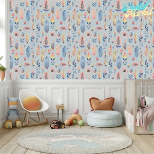 May include: A nursery room with a light blue wallpaper featuring a repeating pattern of colourful leaves and flowers. The room has a rocking chair, a small table, a beanbag chair, and a cot.