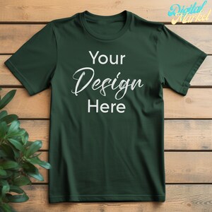 Puede incluir: Una camiseta verde oscuro con un dise&ntilde;o blanco que dice "Your Design Here" sobre un fondo de madera.