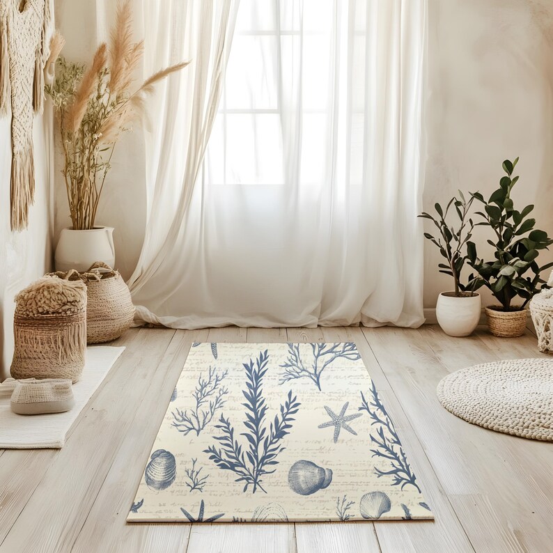 May include: A cream-colored rug with a blue and white seashell and seaweed design. The rug is on a light wood floor in a room with white curtains and a window.