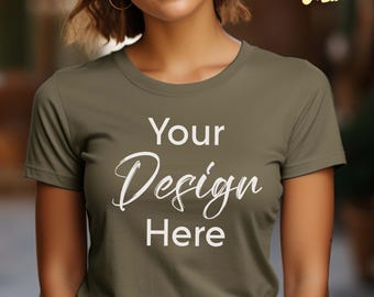 May include: An olive green short-sleeved crew neck t-shirt featuring the white text Your Design Here printed on the front. The shirt has a standard fit with a round neckline and short sleeves, providing a plain surface for custom graphic placement.