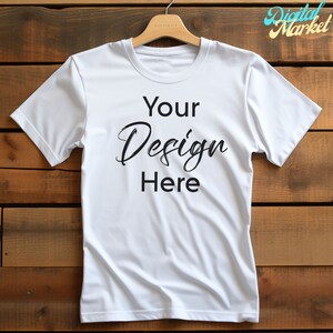 Puede incluir: Camiseta blanca con el texto "Your Design Here" sobre un fondo de madera.