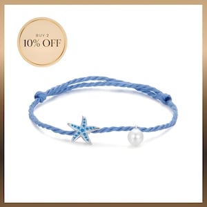 Peut inclure: Un bracelet en cordon bleu clair orné d'une breloque étoile de mer argentée avec de petits accents bleus et d'une perle blanche. Un badge circulaire doré dans le coin supérieur gauche affiche le texte BUY 2 10% OFF.