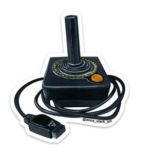 May include: A sticker featuring a black Atari joystick with a black cable and connector. The joystick has a black handle, a yellow circle around the base, and an orange button. The connector has the Atari logo.