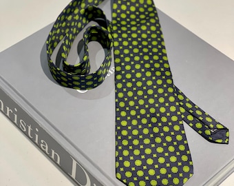 May include: A dark blue silk tie with a green geometric pattern. The tie is on top of a book titled "Christian Dior".