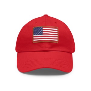 May include: Red baseball cap with a brown leather patch featuring the American flag.
