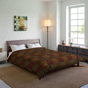 Könnte beinhalten: Ein brauner, grüner und roter karierter Bettbezug auf einem Bett mit weißen Kissen. Das Bett steht in einem Schlafzimmer mit einer weißen Backsteinwand, einem Nachttisch aus Holz und einer Stehlampe.