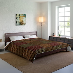 May include: A brown, red, and green plaid comforter on a bed with a wooden headboard. The comforter is folded back to show the white sheets underneath.