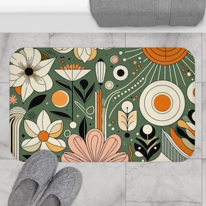 Könnte beinhalten: Eine grüne Badematte mit einem farbenfrohen abstrakten Blumendesign. Das Design zeigt Blumen, Kreise und geometrische Formen in Orange-, Rosa-, Weiß- und Schwarztönen.